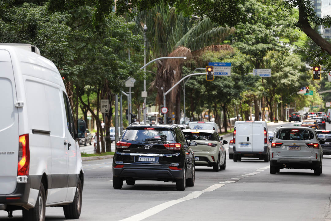 imagem de uma avenida com carros seguindo em direção a semáforo